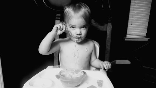 Portrait of boy having food with spoon at table