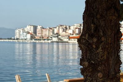 Buildings by sea against clear sky