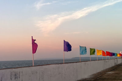 Flag on beach against sky during sunset