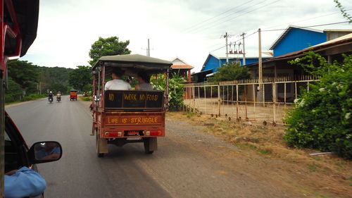 Vehicles on road against sky in city