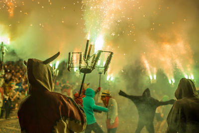 Panoramic view of people holding firework display at night