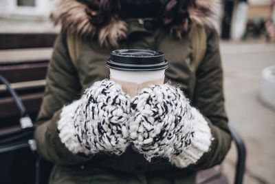 Midsection of woman holding disposable coffee cup