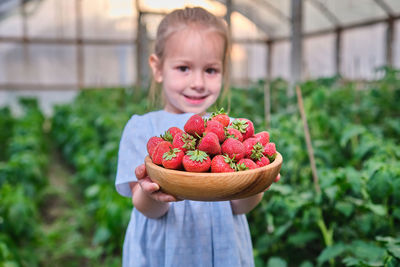 Portrait of cute girl holding strawberries