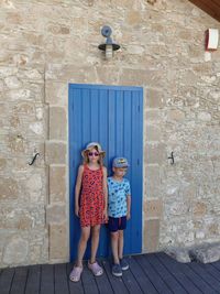 Full length of siblings standing against door