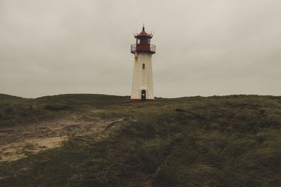 Lighthouse on field against sky