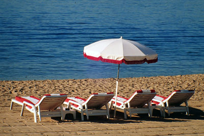 Lounge chairs by parasol at beach