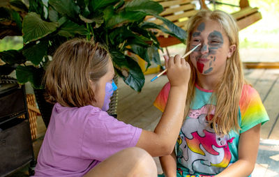 Sisters giggle as they paint each others faces with face paint