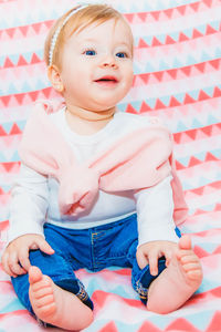 Full length of cute baby girl sitting on bed