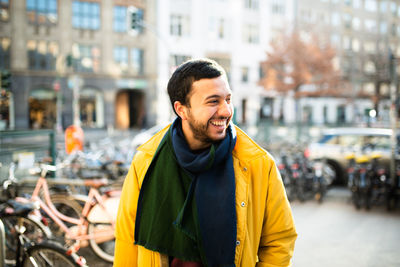 Portrait of smiling young man standing on footpath in city