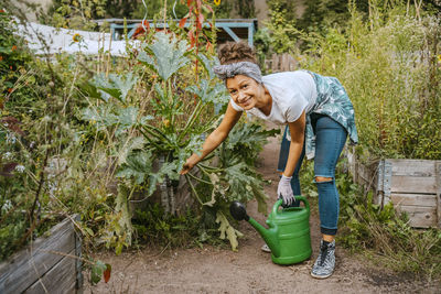 Portrait of smiling female farmer with watering can in farm