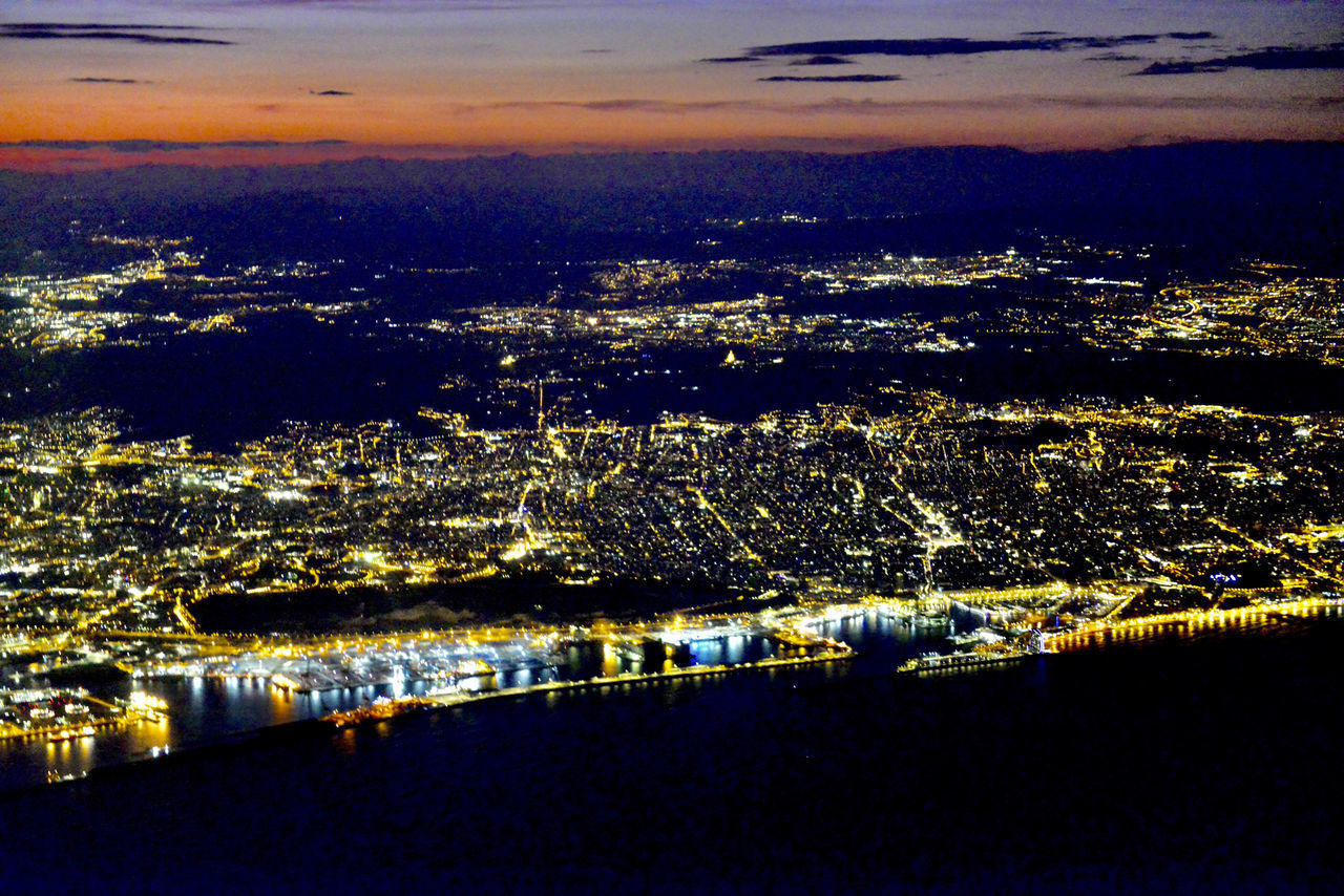 HIGH ANGLE VIEW OF ILLUMINATED CITY BUILDINGS AT NIGHT