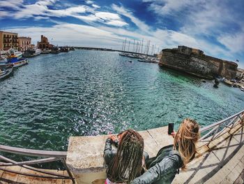 Rear view of people photographing sea against sky