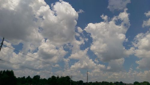 Low angle view of power lines against cloudy sky