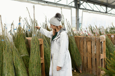 Rear view of female friends standing in greenhouse