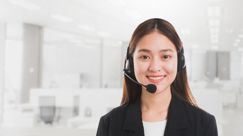 Portrait of smiling businesswoman using headset in office