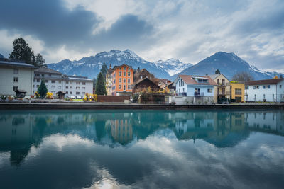 Buildings by lake against sky