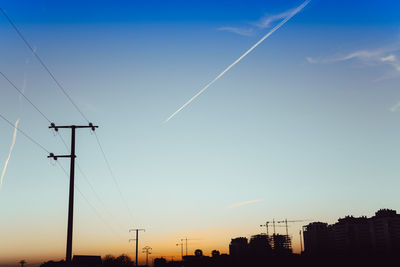 Low angle view of silhouette electricity pylon against sky during sunset