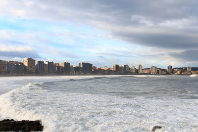 Sea by buildings against sky in city