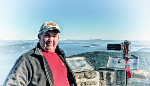 Portrait of man with arms raised against sky
