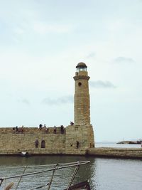 Lighthouse by sea against sky