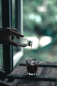 Person pouring drink in glass on table