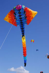 Low angle view of kites against blue sky