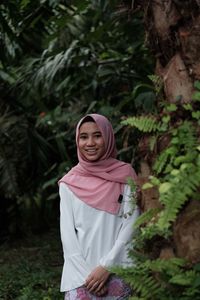 Portrait of smiling teenage girl wearing hijab standing at public park