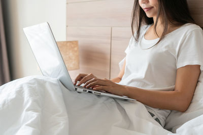 Midsection of woman using laptop at home