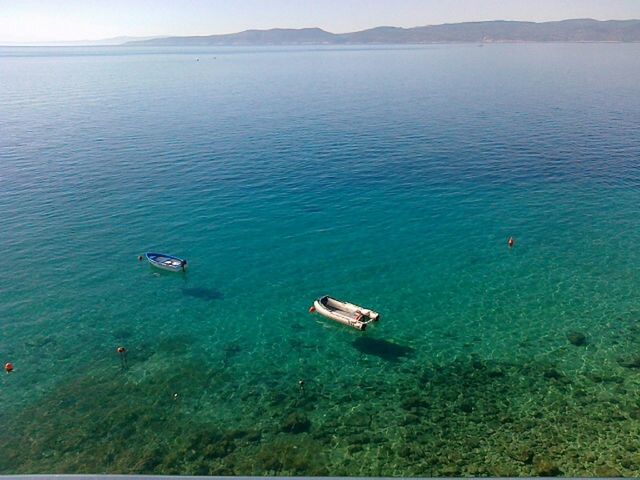 nautical vessel, water, transportation, boat, high angle view, mode of transport, tranquil scene, scenics, tranquility, sea, blue, travel, beauty in nature, nature, mountain, tourism, travel destinations, non-urban scene, vacations, elevated view, sky, outdoors, seascape, day, journey, coastline, mountain range, no people