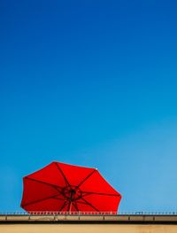 Red umbrella against clear blue sky