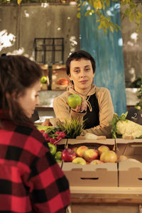 Portrait of young woman holding food on table