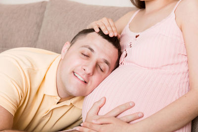 Midsection of woman with baby girl lying on bed