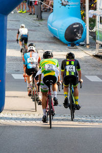 Rear view of people riding bicycle on road