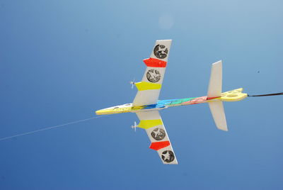 Low angle view of airplane flying against clear blue sky