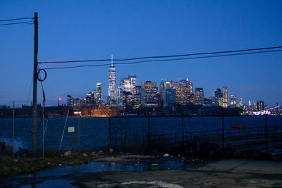 Illuminated buildings in city against clear sky