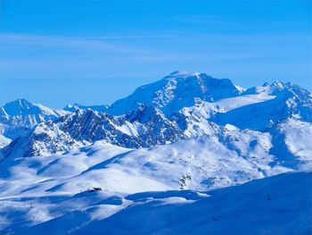 Scenic view of snowcapped mountains against blue sky