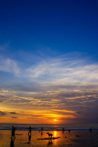 Silhouette people on beach against sky during sunset