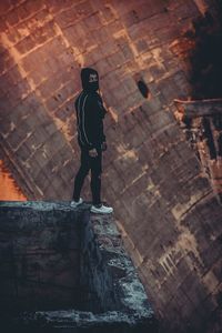 Rear view of man standing on rock against building
