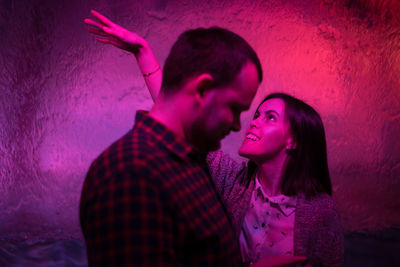 Side view of man standing by happy woman dancing in nightclub