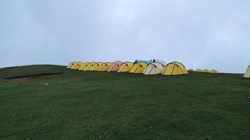 Multi colored umbrellas on field against sky