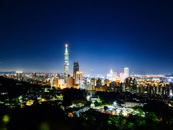 Illuminated buildings in city against sky at night