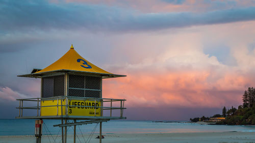 Lifeguard hut on beach against sky during sunset