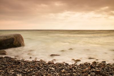 Romantic atmosphere in peaceful morning at sea. big boulders in smooth wavy sea. pink horizon 