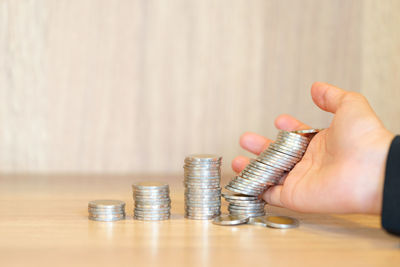 Close-up of hand holding coins on table