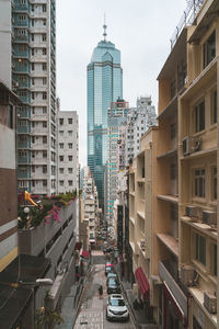 Vehicles on road amidst buildings in city against sky