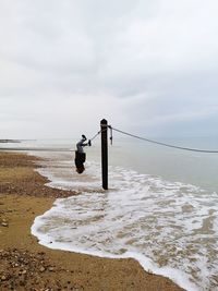 Rear view of boy walking on beach against sky