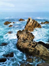 Rocks on shore by sea against sky