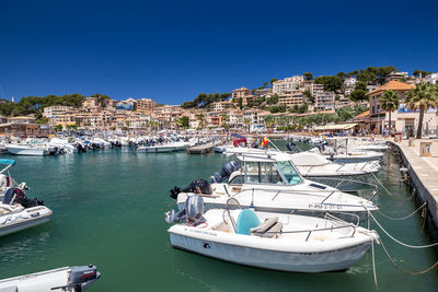 Sailboats moored in harbor against clear blue sky