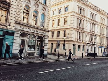 People walking on road amidst buildings in city