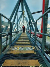 Rear view of man walking on bridge